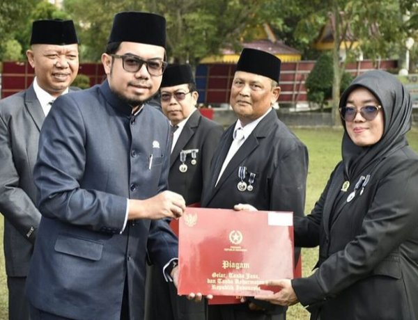 Wakil Ketua DPRD Kota Pekanbaru Ginda Burnama MT saat menyerahkan piagam tanda kehormatan Satya Lencana Karya Satya dari Presiden RI kepada salah satu peserta